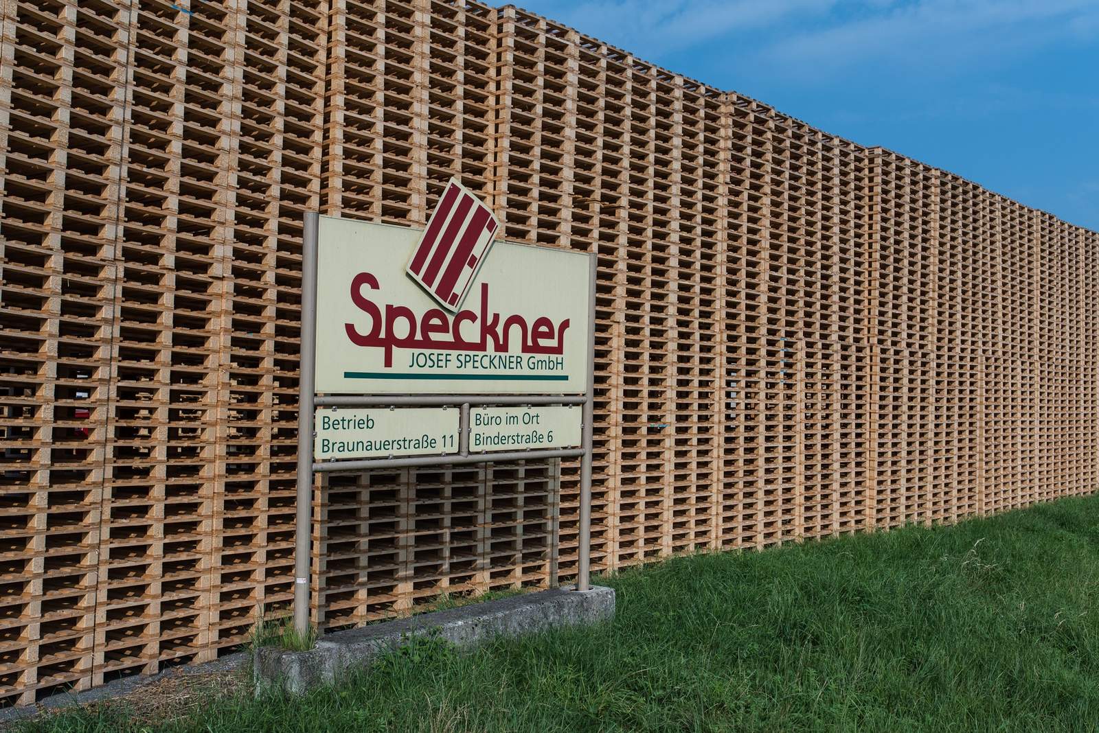 Firmenschild vor einem Palettenstapel