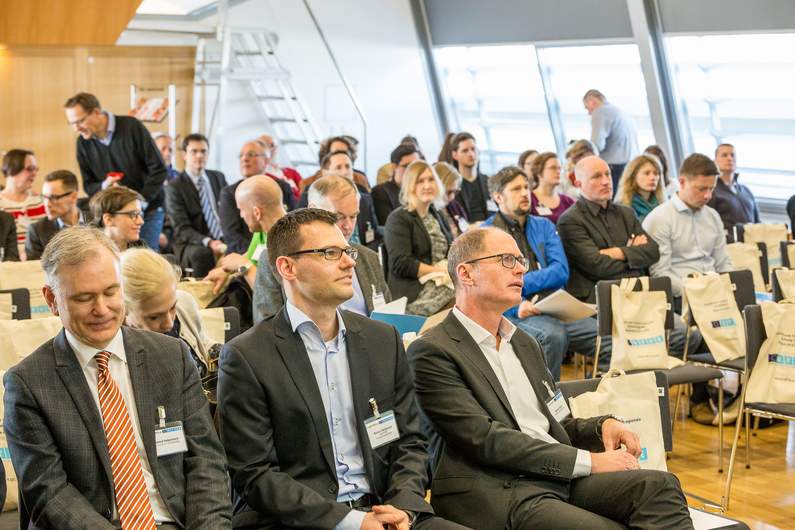 Foto vollbesetzter Veranstaltungssaal der Urania, im Vordergrund Markus McDowell und Markus Seidl von der IWB/EFRE-Verwaltungsbehörde