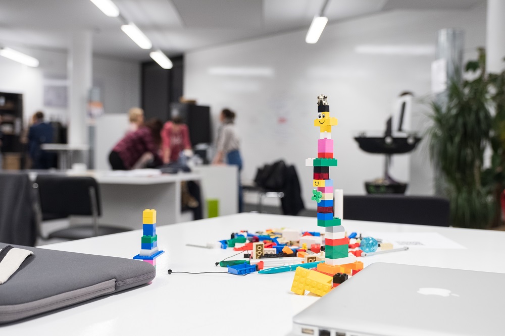 Foto des Build Gründerzentrums mit Legoturm und Personengruppe im Hintergrund