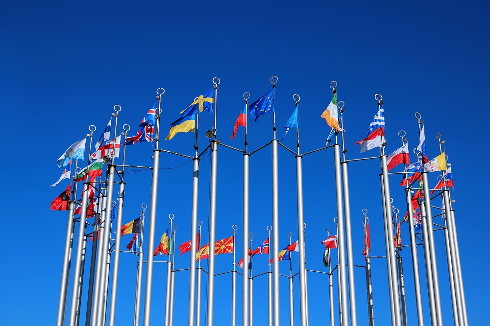 Foto Fahnenmasten mit Flaggen der EU-Mitgliedsländer vor blauem Himmel