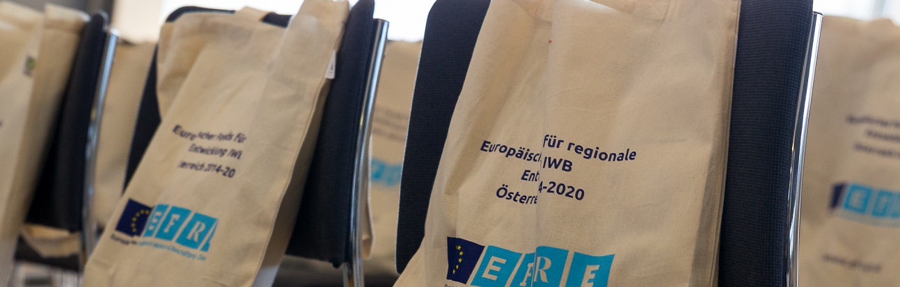 Foto von Konferenztaschen mit IWB/EFRE-Logo auf Veranstaltungssesseln