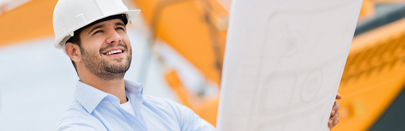 Architekt auf einer Baustelle mit einem Plan in beiden Händen. 