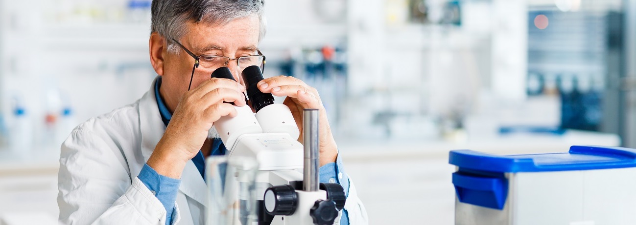 Mann sitzt in einem modernen Forschungslabor und blickt durch ein Mikroskop. Das Bild dient als Beispiel für mit IWB/EFRE-Mitteln geförderte Projekte im Bereich Forschung & Entwicklung. 