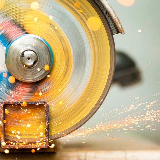 Eine Metallkreissäge schneidet ein Stück eines quadratischen Metallrohres ab. Das Bild symbolisiert förderbare Investitionen von Klein- und Mittelbetrieben zur Stärkung der Wettbewerbsfähigkeit im Rahmen des IWB/EFRE-Förderprogramms.