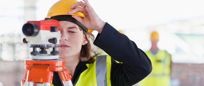 Vermessungstechnikerin blickt bei der Arbeit durch ein Vermessungsgerät. Das Bild ist ein Symbol für förderfähige Bau- und Infrastrukturprojekte des IWB/EFRE-Förderprogramms.